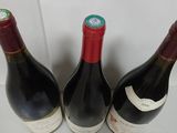 three bottles of red wine are lined up on a table