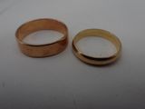 two wedding rings sitting on a table next to each other