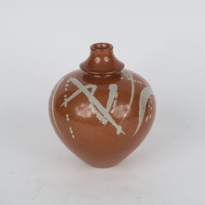 un vase brun orné d'un motif sur une surface blanche