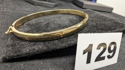 un bracelet en or posé sur un morceau de tissu, avec une étiquette de prix