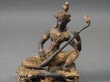 a bronze statue of a man playing a musical instrument on a rock