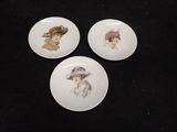 three plates with pictures of women in hats on them on a black surface