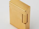 a gold cigarette lighter sitting on top of a white surface