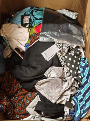 une boîte en carton remplie de vêtements et des vêtements par terre