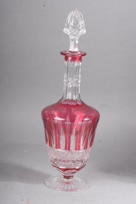 une carafe en verre rose avec un bouchon transparent, posée sur une surface blanche