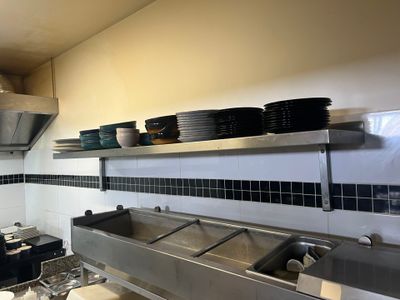 a kitchen with a stove, sink, and a counter with dishes on it