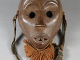 un vieux masque en bois au visage brun, suspendu à une ficelle