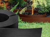 un gros plan sur une jardinière en plastique noir dans un jardin