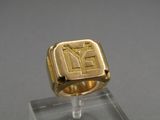 a close up of a gold signet ring on a clear stand