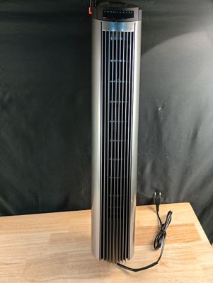 un ventilateur électrique posé sur une table en bois, près d'un mur noir