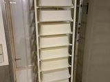 a tall white shelf in the corner of a room