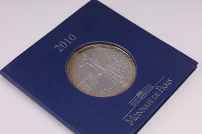 un gros plan d'une pièce de monnaie dans une boîte bleue posée sur une surface blanche