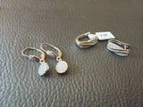 deux paires de boucles d'oreilles posées sur une surface en cuir