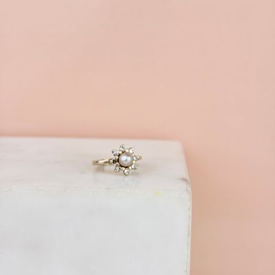 un gros plan d'une bague de fiançailles en diamant posée sur un bloc de marbre blanc