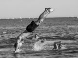 photographie en noir et blanc d'un homme faisant le poirier dans l'eau