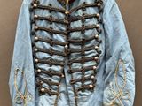 une vieille veste militaire bleue à boutons dorés, suspendue à un cintre