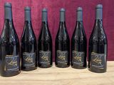 six bouteilles de vin sont alignées sur une table en bois