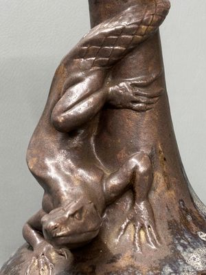 une statue en bronze représentant un homme et un chien, posée sur un vase