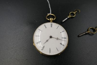 une montre de poche avec une clé posée sur une table