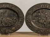 two metal plates with designs on them on a table