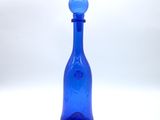 blue glass bottle with a blue stopper sitting on a white surface