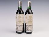 two bottles of red wine sitting next to each other on a table