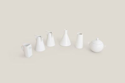 Plusieurs vases blancs sont disposés en rangée sur une surface grise