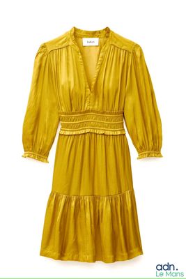 La robe est jaune et ornée de volants.