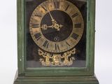 a green clock with a gold face and a key in front of it