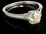 un gros plan d'une bague sertie d'un diamant jaune sur une surface noire