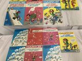 une pile de livres pour enfants posée sur un lit aux draps blancs