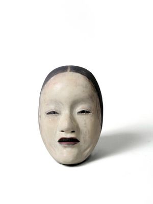 un masque blanc orné d'un bandeau noir sur un fond blanc