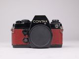 L'appareil photo est rouge et noir, avec un objectif noir.