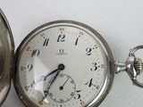 a silver pocket watch sitting on a white surface