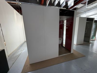 une pièce avec une cloison blanche et une porte rouge
