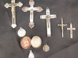 de nombreuses croix en argent et d'autres objets religieux posés sur un tissu noir