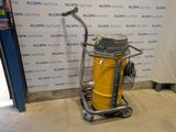 a yellow and black vacuum on a cart in front of a wall