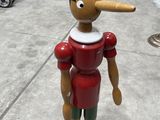 wooden figurine of a man with a pipe sticking out of his nose