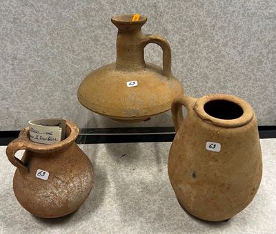 trois vases en argile, munis d'étiquettes, posés sur une table