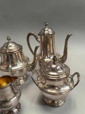 three pieces of silver tea and coffee set on a table
