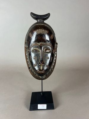 un gros plan d'une sculpture représentant un visage surmonté d'un oiseau