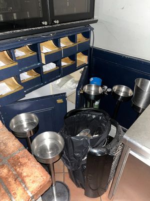 de nombreuses casseroles et poêles dans la cuisine, à côté d'une poubelle