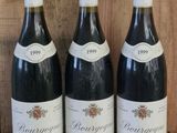 three bottles of wine sit on a shelf in front of a wooden wall