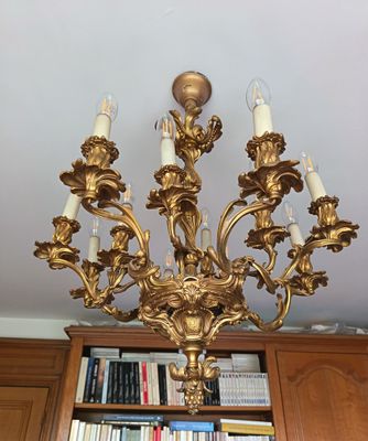 un lustre doré dans un salon, avec des bibliothèques en arrière-plan