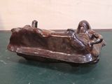 statue of a woman laying on a couch on a green surface