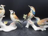 trois figurines d'oiseaux perchés sur une branche, sur fond noir