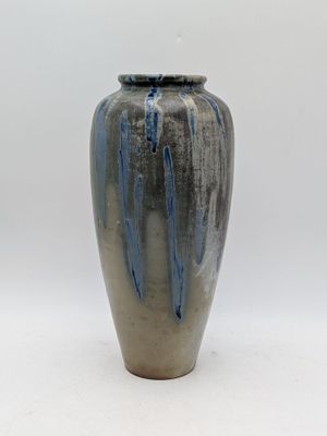 un vase bleu et gris posé sur une surface blanche