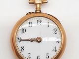 gros plan d'une montre de poche en or sur une surface blanche
