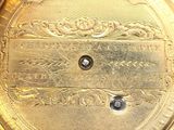 a close up of a gold pocket watch on a white surface