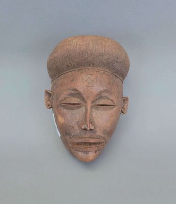 un masque en bois accroché au mur d'une pièce